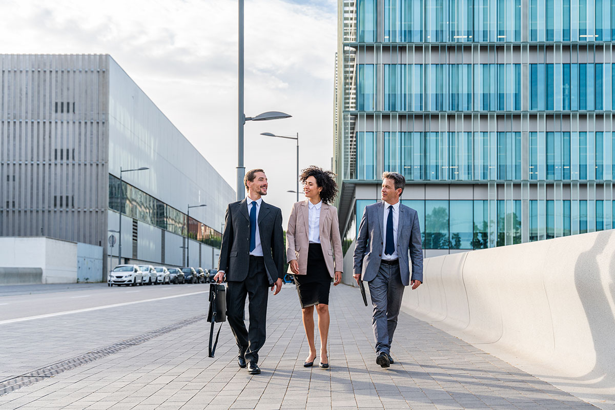 Equipo de profesionales caminando frente a edificios de oficinas